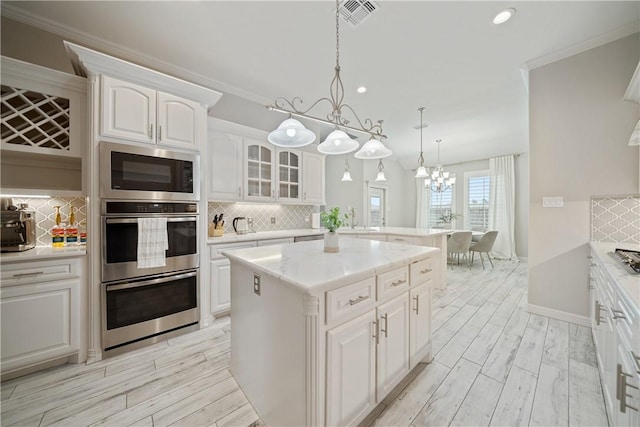 kitchen featuring visible vents, decorative backsplash, light countertops, wood finish floors, and double oven