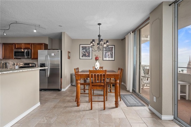 dining space with a notable chandelier, light tile patterned floors, a textured ceiling, and baseboards