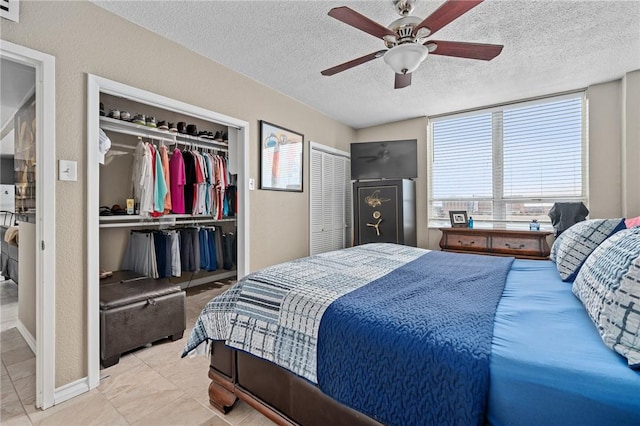 bedroom featuring a ceiling fan, a closet, a textured wall, and a textured ceiling