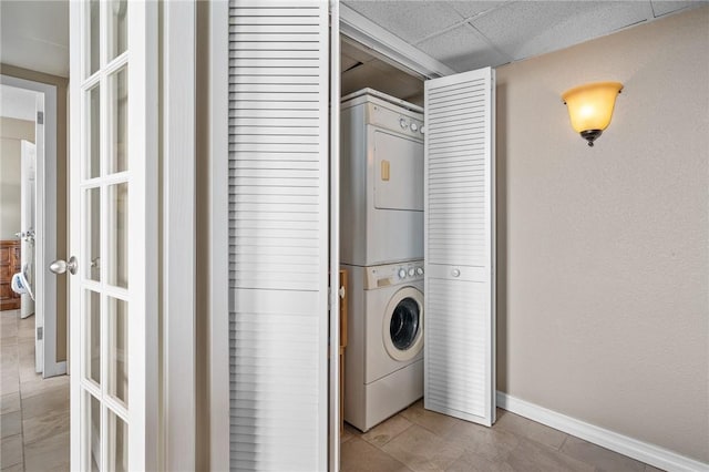 laundry room featuring laundry area, stacked washing maching and dryer, and baseboards