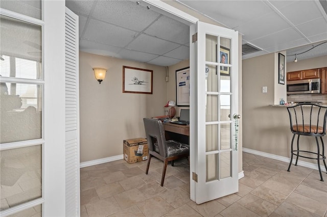 office area with visible vents, a paneled ceiling, and baseboards