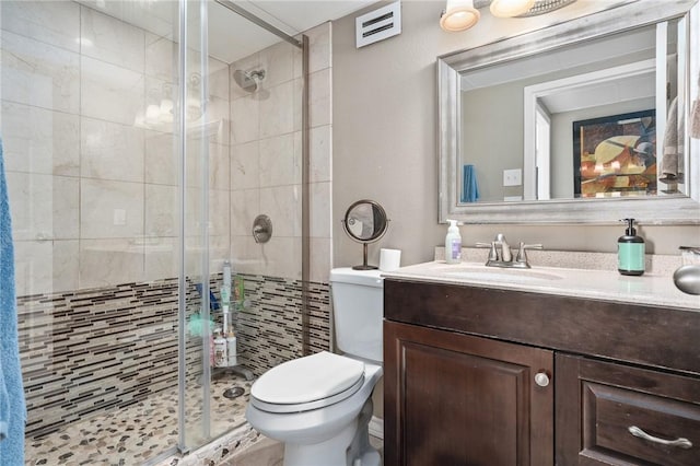 bathroom featuring visible vents, vanity, a shower stall, and toilet