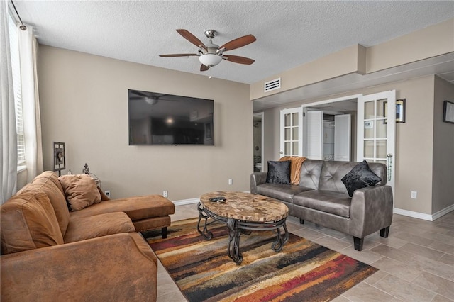 living room featuring baseboards, visible vents, ceiling fan, and a textured ceiling