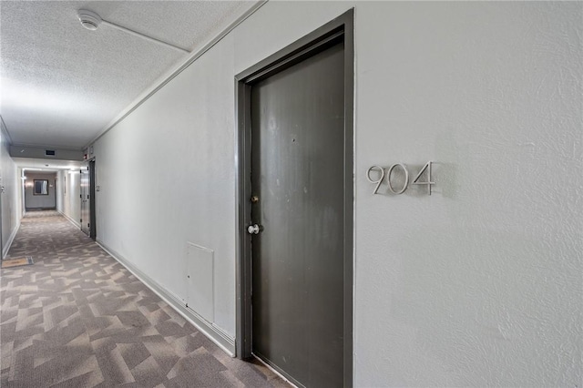 hallway featuring carpet floors and a textured ceiling