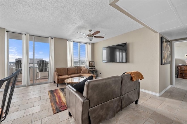 living area featuring a textured ceiling, ceiling fan, light tile patterned floors, baseboards, and a wall of windows