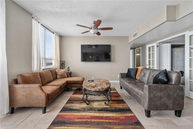 living room with visible vents, ceiling fan, a textured ceiling, and stacked washing maching and dryer