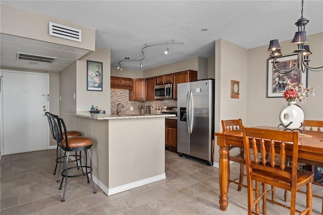 kitchen with a peninsula, visible vents, appliances with stainless steel finishes, and tasteful backsplash