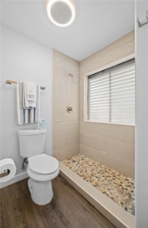 bathroom with toilet, wood-type flooring, and a tile shower