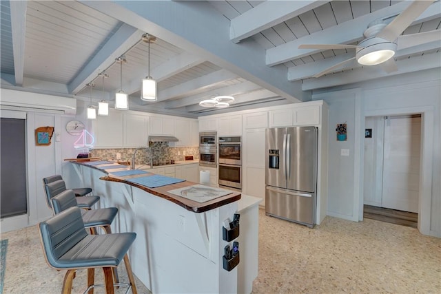 kitchen with appliances with stainless steel finishes, pendant lighting, a wall mounted air conditioner, tasteful backsplash, and white cabinetry