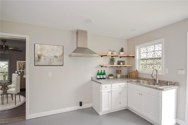 105 E Cornwall St, Rockport, TX 78382 - kitchen featuring wall chimney range hood, a sink, white cabinetry, baseboards, and light countertops
