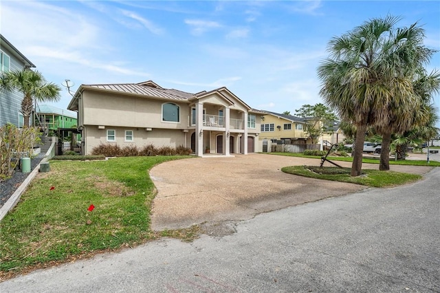 view of front of property featuring concrete driveway, stucco siding, metal roof, a balcony, and a standing seam roof