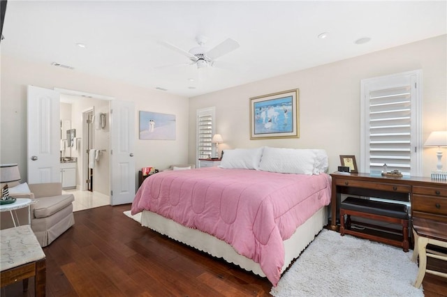 bedroom with ceiling fan, visible vents, ensuite bath, and wood finished floors