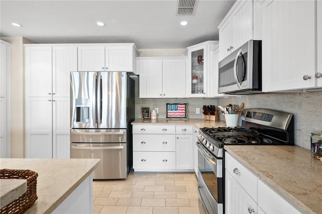 kitchen with tasteful backsplash, white cabinetry, and stainless steel appliances