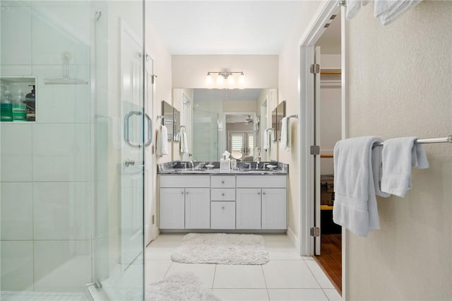 full bath with tile patterned flooring, double vanity, a stall shower, and a sink