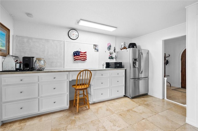 kitchen featuring white cabinetry, arched walkways, stainless steel fridge with ice dispenser, light countertops, and built in study area