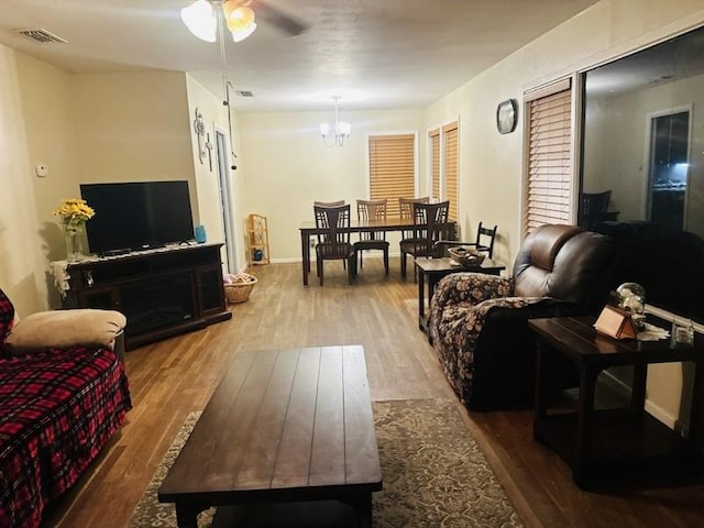 living room featuring ceiling fan with notable chandelier and hardwood / wood-style flooring