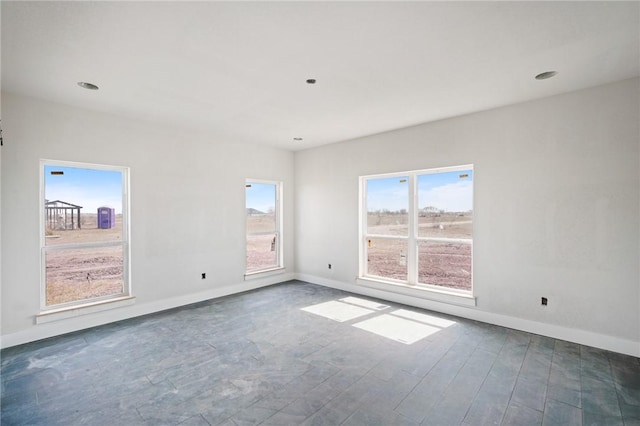 spare room featuring plenty of natural light, baseboards, and dark wood-style flooring