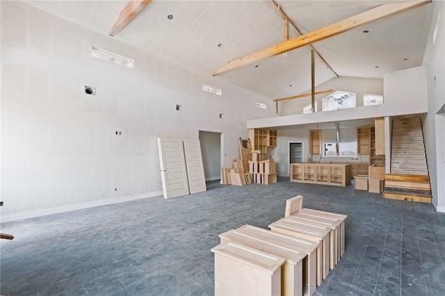 interior space featuring high vaulted ceiling, beamed ceiling, baseboards, and stairs