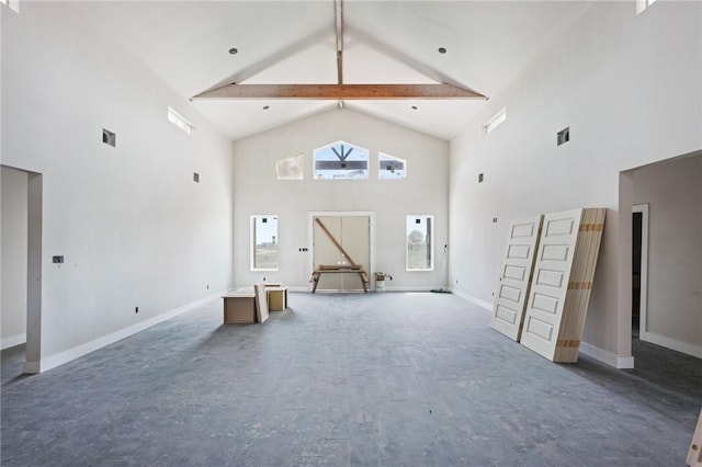 unfurnished living room with high vaulted ceiling, beamed ceiling, and baseboards