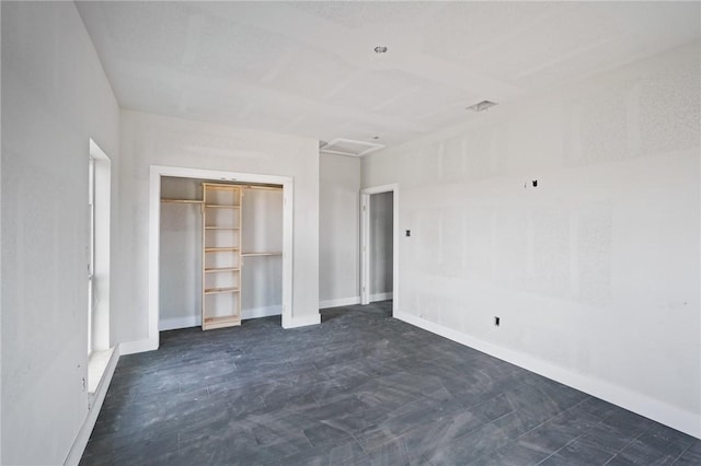 unfurnished bedroom with attic access, a closet, and baseboards