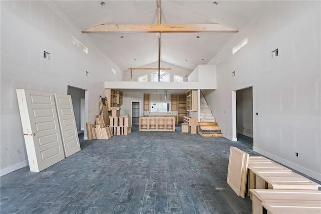 unfurnished living room with baseboards, stairway, wood finished floors, beamed ceiling, and high vaulted ceiling