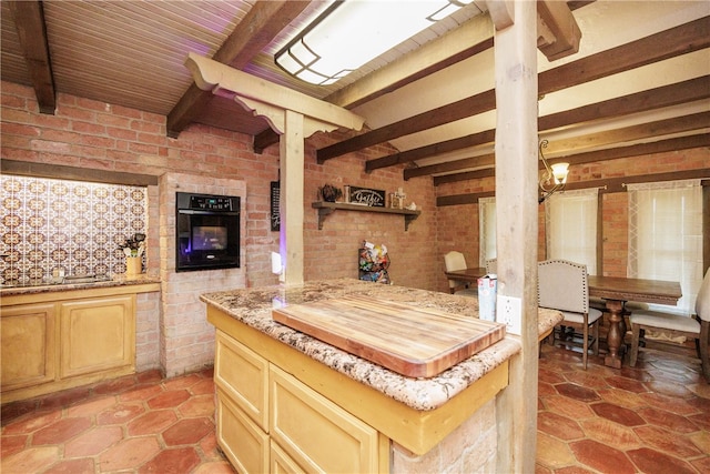 kitchen with oven, beam ceiling, brick wall, and a center island