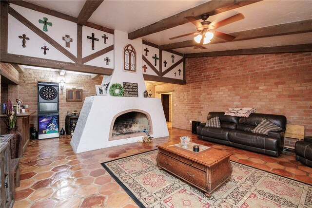 living room featuring beam ceiling, ceiling fan, and brick wall