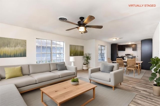 living room with plenty of natural light, ceiling fan, and light wood-type flooring