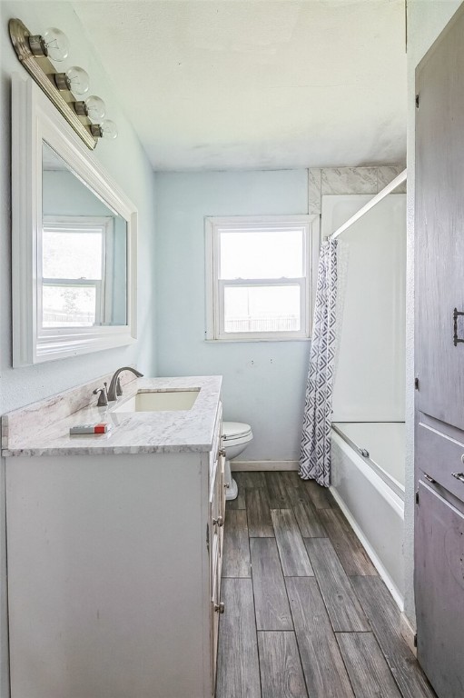 full bathroom featuring wood tiled floor, plenty of natural light, vanity, and toilet