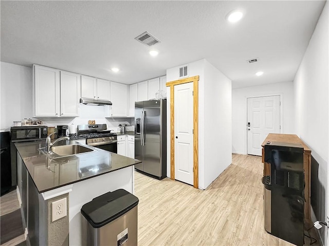 3221 Wrangler St, Corpus Christi, TX 78410 - kitchen featuring stainless steel appliances, under cabinet range hood, a peninsula, dark countertops, and white cabinetry