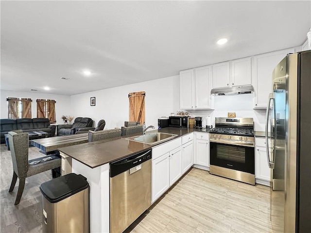 kitchen featuring kitchen peninsula, appliances with stainless steel finishes, white cabinets, and sink