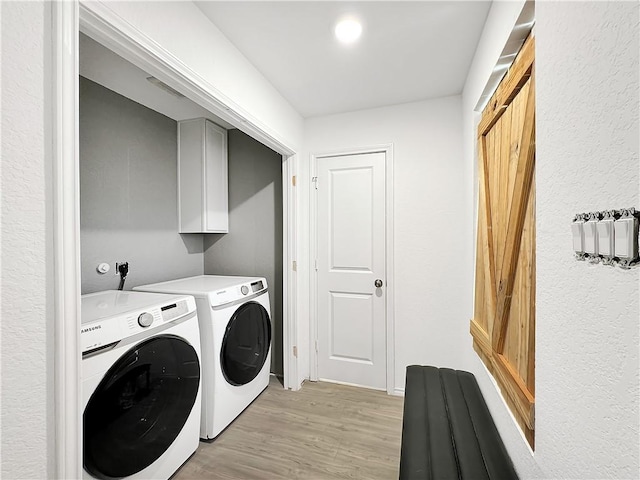 washroom with cabinets, independent washer and dryer, and light wood-type flooring