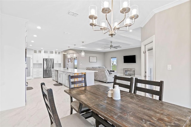 dining area with ceiling fan with notable chandelier, sink, and ornamental molding