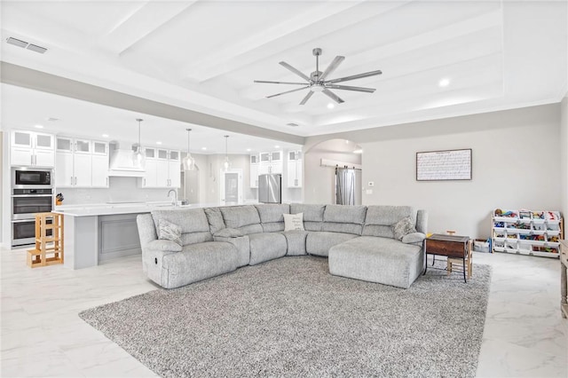 living room with sink, a raised ceiling, and ceiling fan