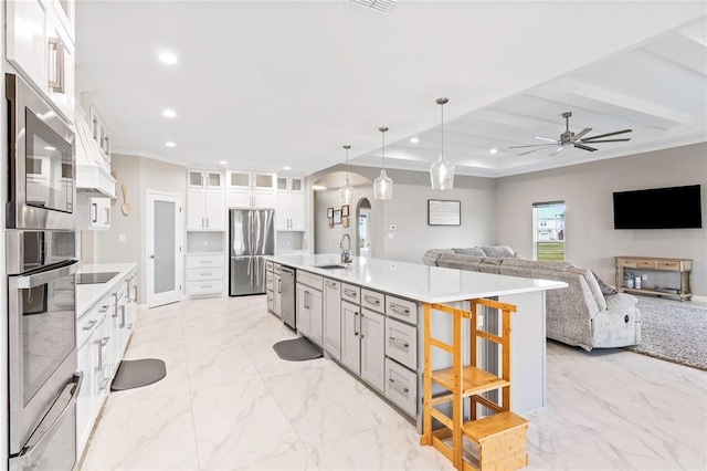 kitchen with white cabinetry, ceiling fan, hanging light fixtures, a kitchen island with sink, and appliances with stainless steel finishes