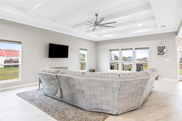 living room with ceiling fan, a tray ceiling, and a healthy amount of sunlight