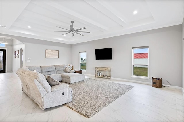 living room featuring ceiling fan, a raised ceiling, ornamental molding, and a wealth of natural light