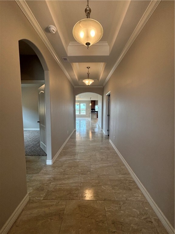 hall with crown molding and a tray ceiling