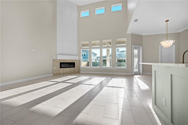 living area with visible vents, baseboards, a chandelier, a tiled fireplace, and a high ceiling