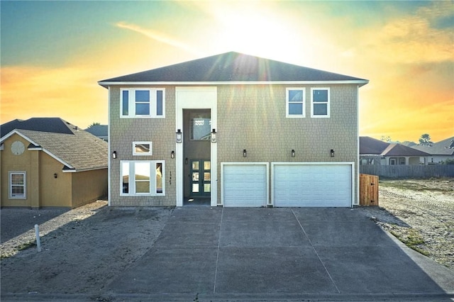 view of front of property featuring an attached garage, driveway, and fence