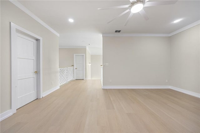 empty room with crown molding, visible vents, light wood-type flooring, and baseboards