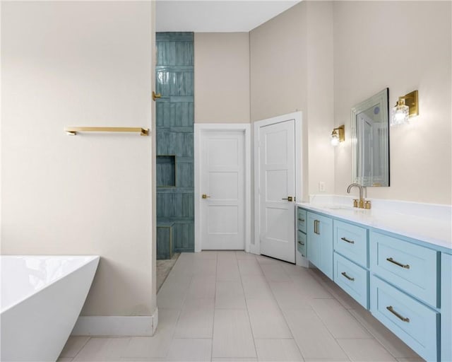 bathroom featuring a high ceiling, tile patterned flooring, baseboards, a freestanding bath, and vanity