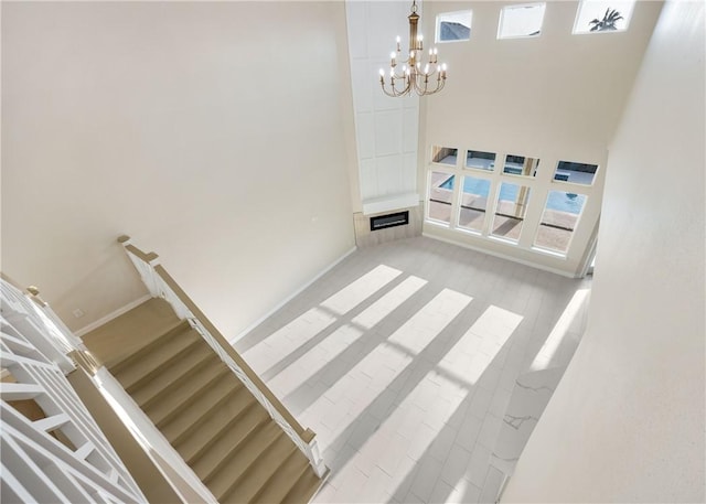 interior space featuring a notable chandelier, a high ceiling, baseboards, and wood finished floors