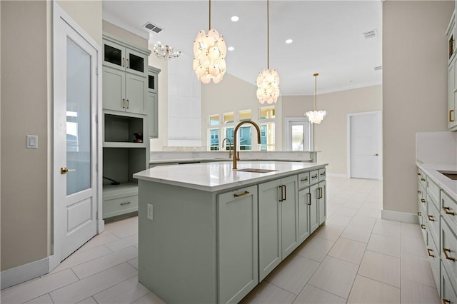 kitchen with a sink, visible vents, an island with sink, and light countertops