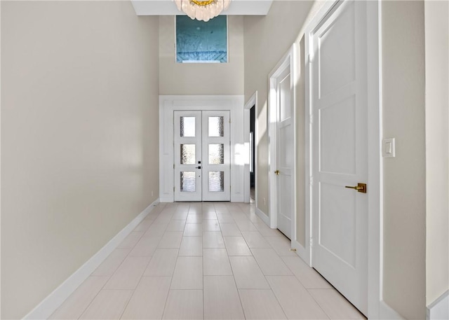 foyer entrance featuring light tile patterned floors, french doors, baseboards, and a towering ceiling