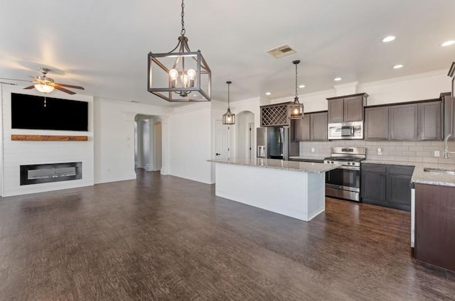 kitchen with visible vents, a sink, a glass covered fireplace, a center island, and stainless steel appliances