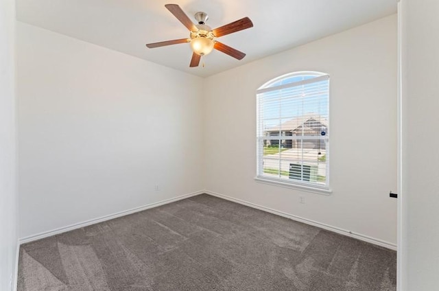 spare room with ceiling fan, baseboards, and dark colored carpet