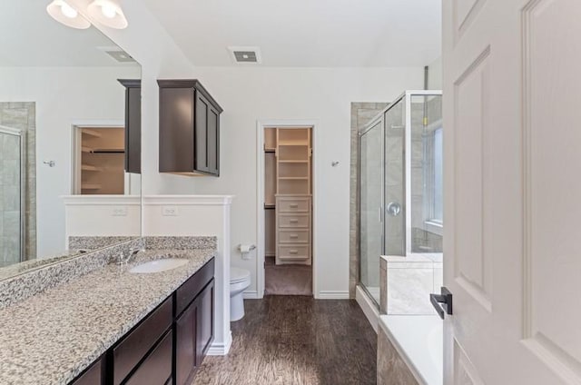 bathroom featuring a walk in closet, toilet, and a shower stall