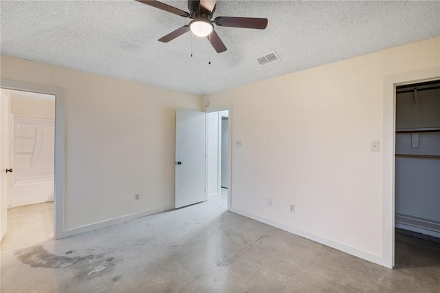 unfurnished bedroom featuring ceiling fan, a spacious closet, a textured ceiling, and a closet