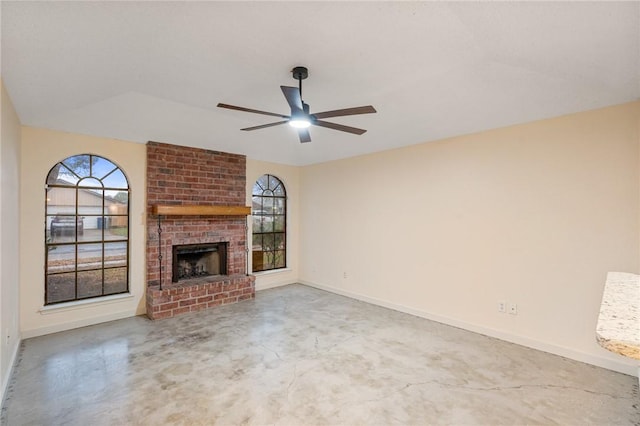 unfurnished living room featuring ceiling fan, concrete flooring, a brick fireplace, and a wealth of natural light